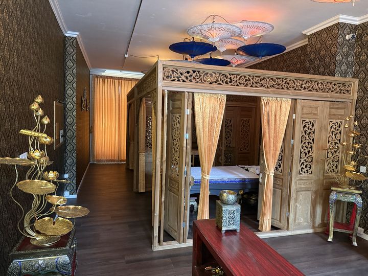 Teak-Kabine mit Vorhängen, daneben goldene Lotusblüten aus Bangkok